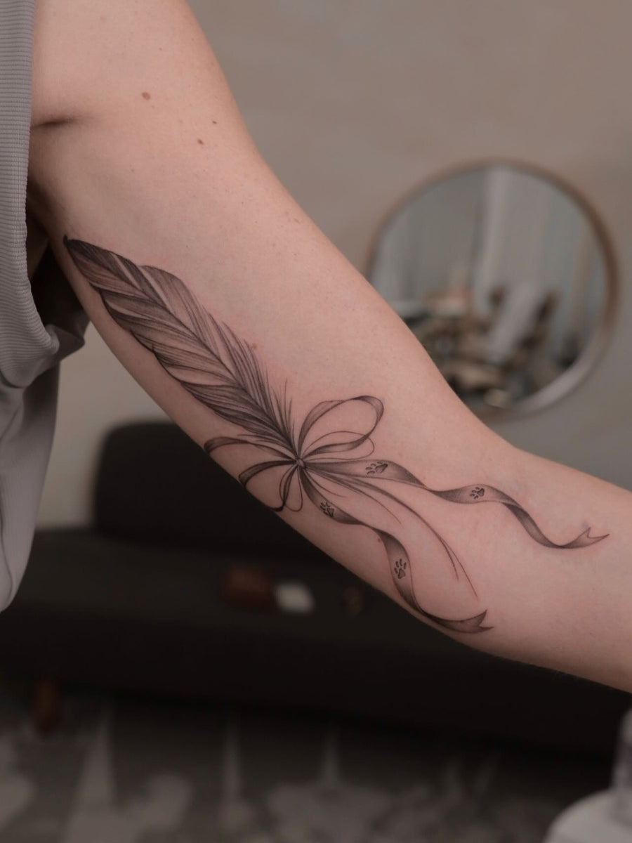 Fine line ribbon and feather tattoo by Kim